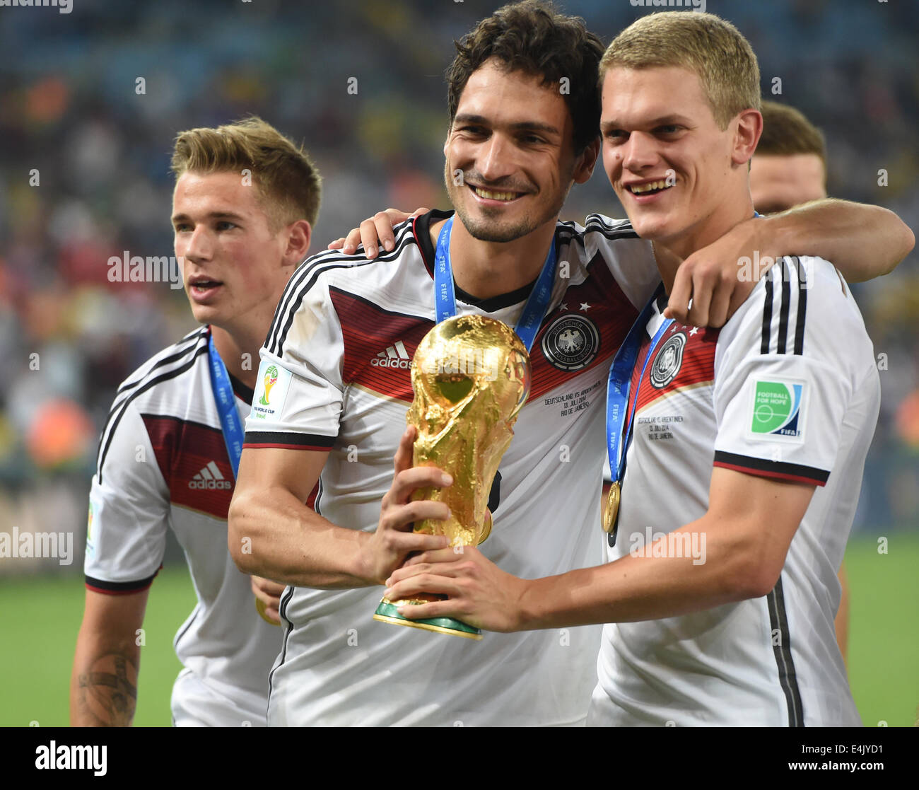 Rio de Janeiro, Brazil. 13th July, 2014. Germany's Erik Durm, (L-R) Mats Hummels and Matthias Ginter celebrate on the pitch with the World Cup trophy after winning the FIFA World Cup 2014 final soccer match between Germany and Argentina at the Estadio do Maracana in Rio de Janeiro, Brazil, 13 July 2014. Photo: Marcus Brandt/dpa/Alamy Live News Stock Photo