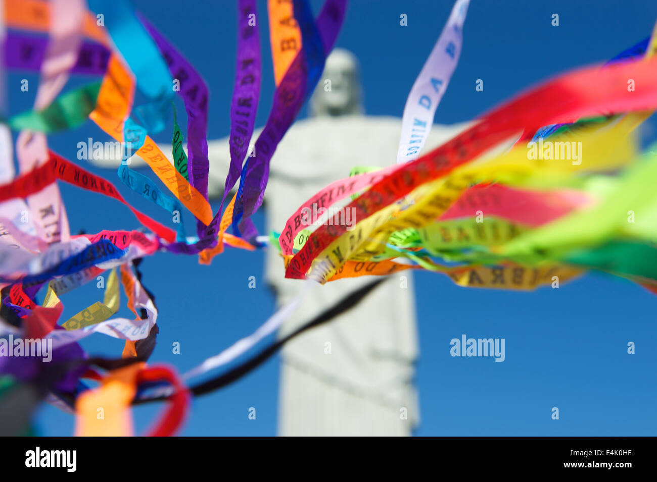 Bright and colorful Brazilian wish ribbons flying in blue sky Corcovado Christ the Redeemer statue Rio de Janeiro Stock Photo