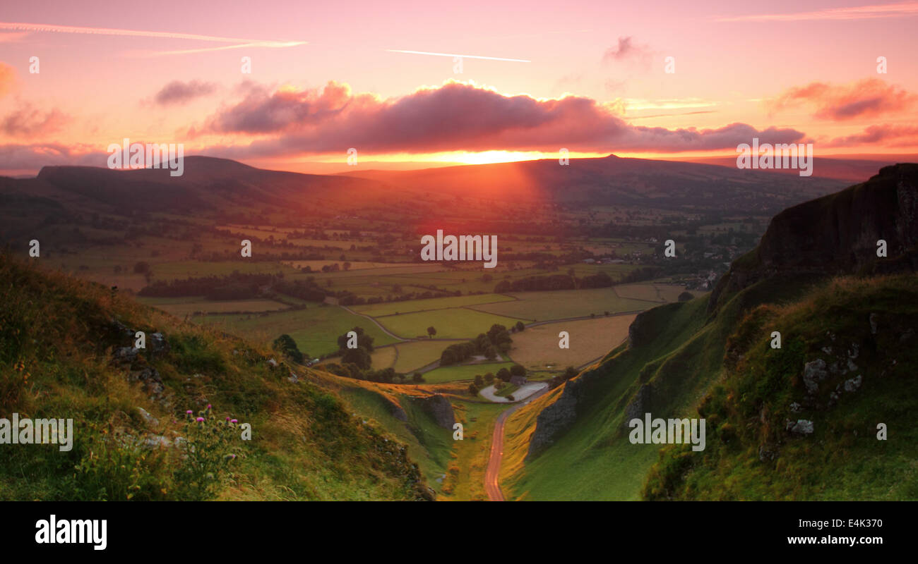 Peak District, Derbyshire, UK. 14 July 2014.  A surge of scarlet dawn light illumiinates the Hope Valley below Winnats Pass at Castleton in Derbyshire's Peak District National Park. Though some parts of the UK will see patchy rain today, heat is forecast to build during the week. Credit:  Matthew Taylor/Alamy Live News Stock Photo
