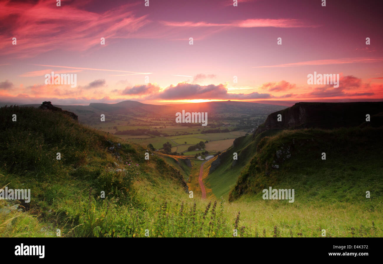 Peak District, Derbyshire, UK. 14 July 2014.  A surge of scarlet dawn light illuminates the Hope Valley below Winnats Pass at Castleton in Derbyshire's Peak District National Park. Though some parts of the UK will see patchy rain today, heat is forecast to build during the week. Credit:  Matthew Taylor/Alamy Live News Stock Photo