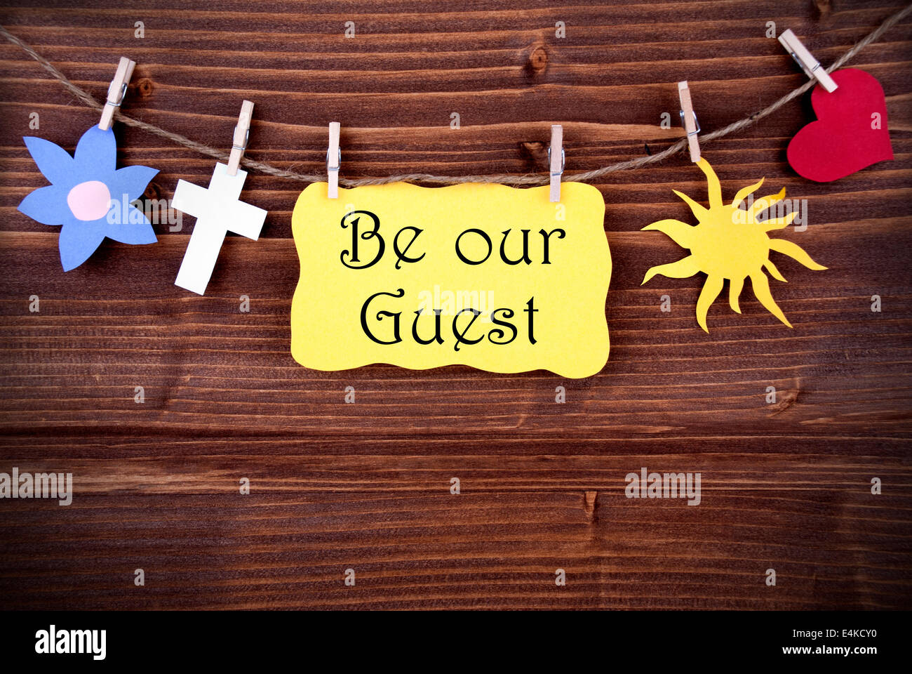 Hanging Tag with the Words Be Our Guest and Some Symbolics on Wood Stock Photo