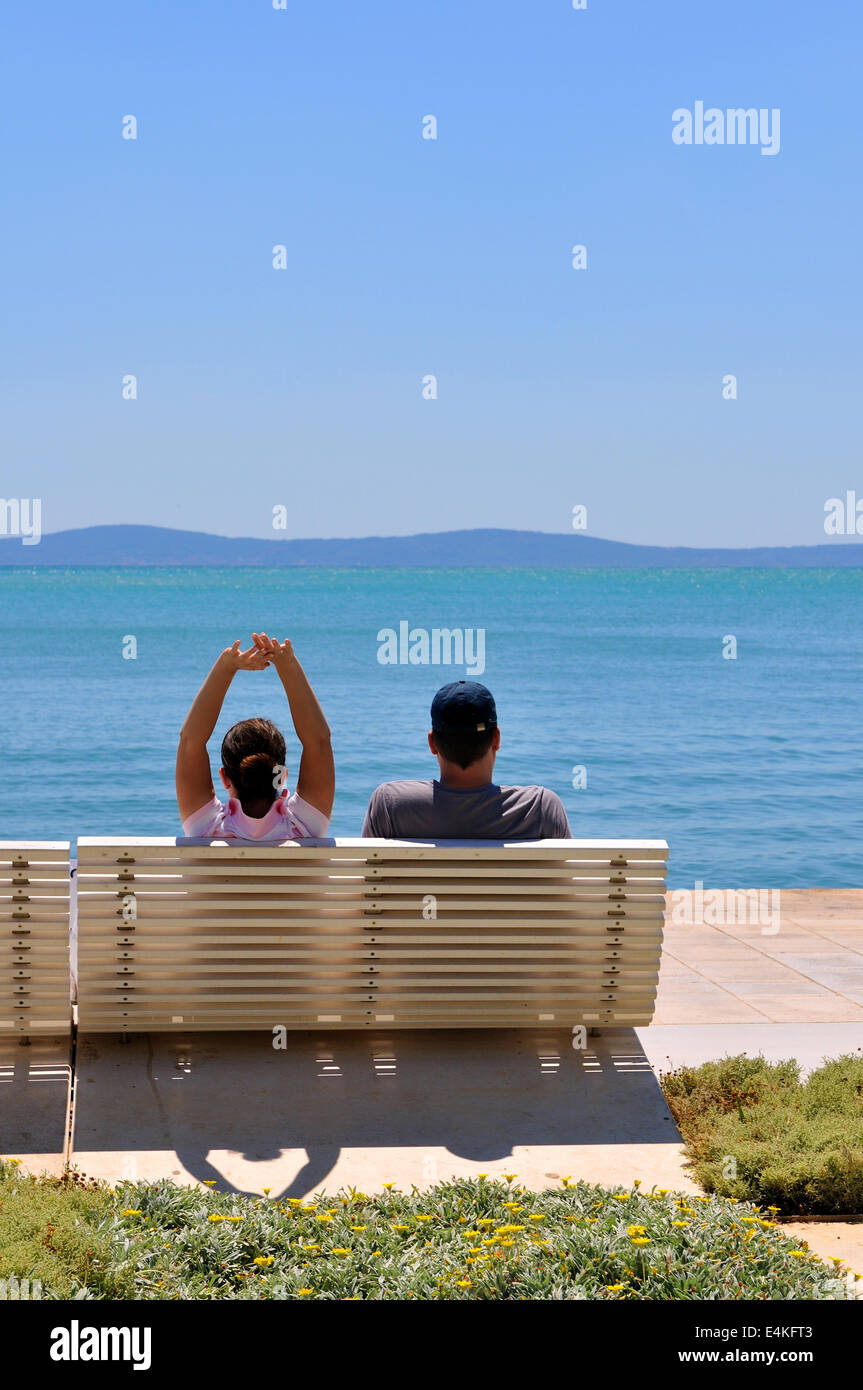 Happy young couple sitting on the beach Stock Photo - Alamy