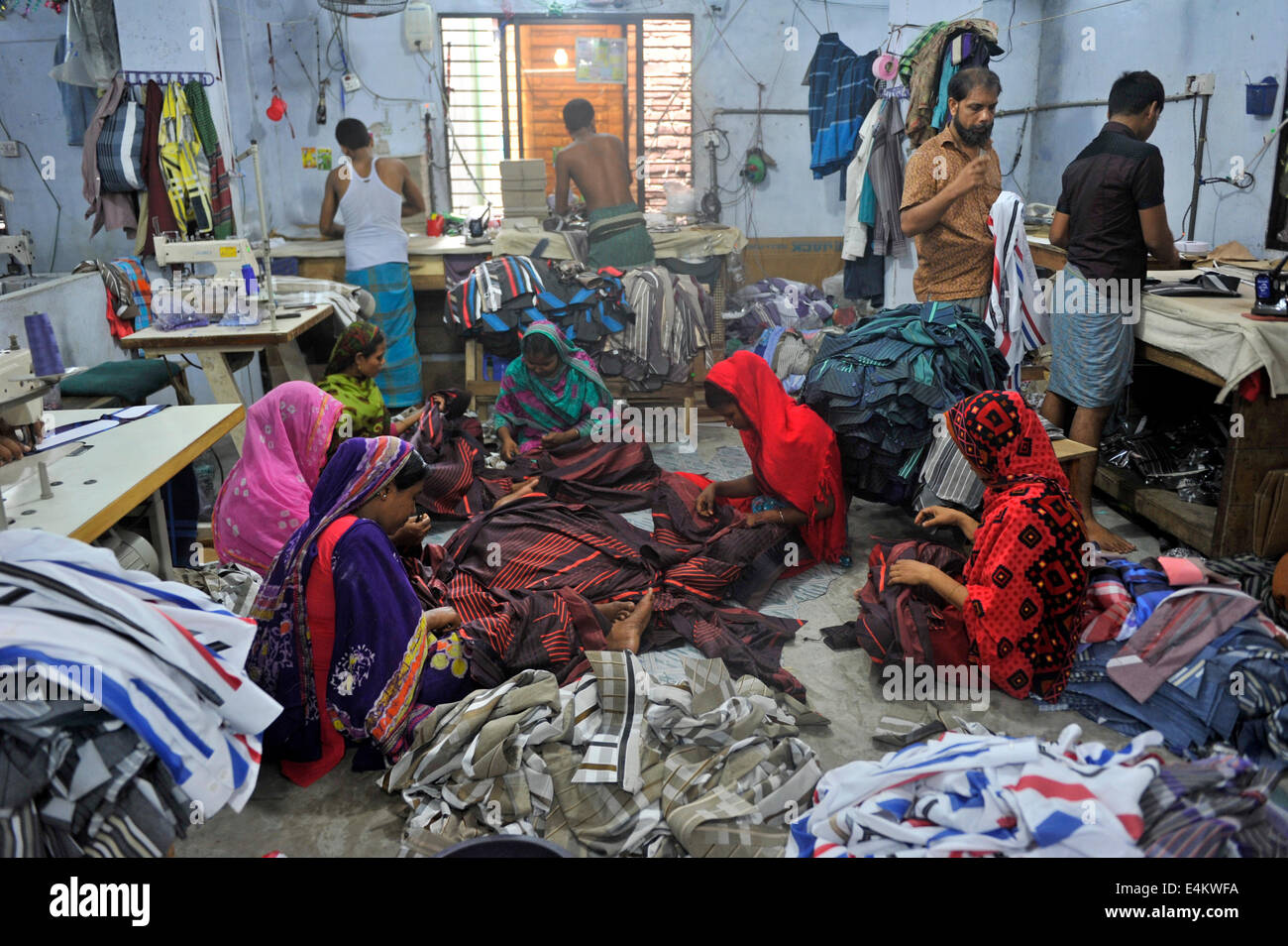 Bangladeshi garment workers on the floor while sewing clothes for the domestic market in Keranigonj at Dhaka. Some garment factories located near Buriganga river side at Keranigonj in Dhaka do not have sufficient facilities for workers such as air and light and the worst, workers salary is very low and not paid on time. © Mohammad Asad/Pacific Press/Alamy Live News Stock Photo