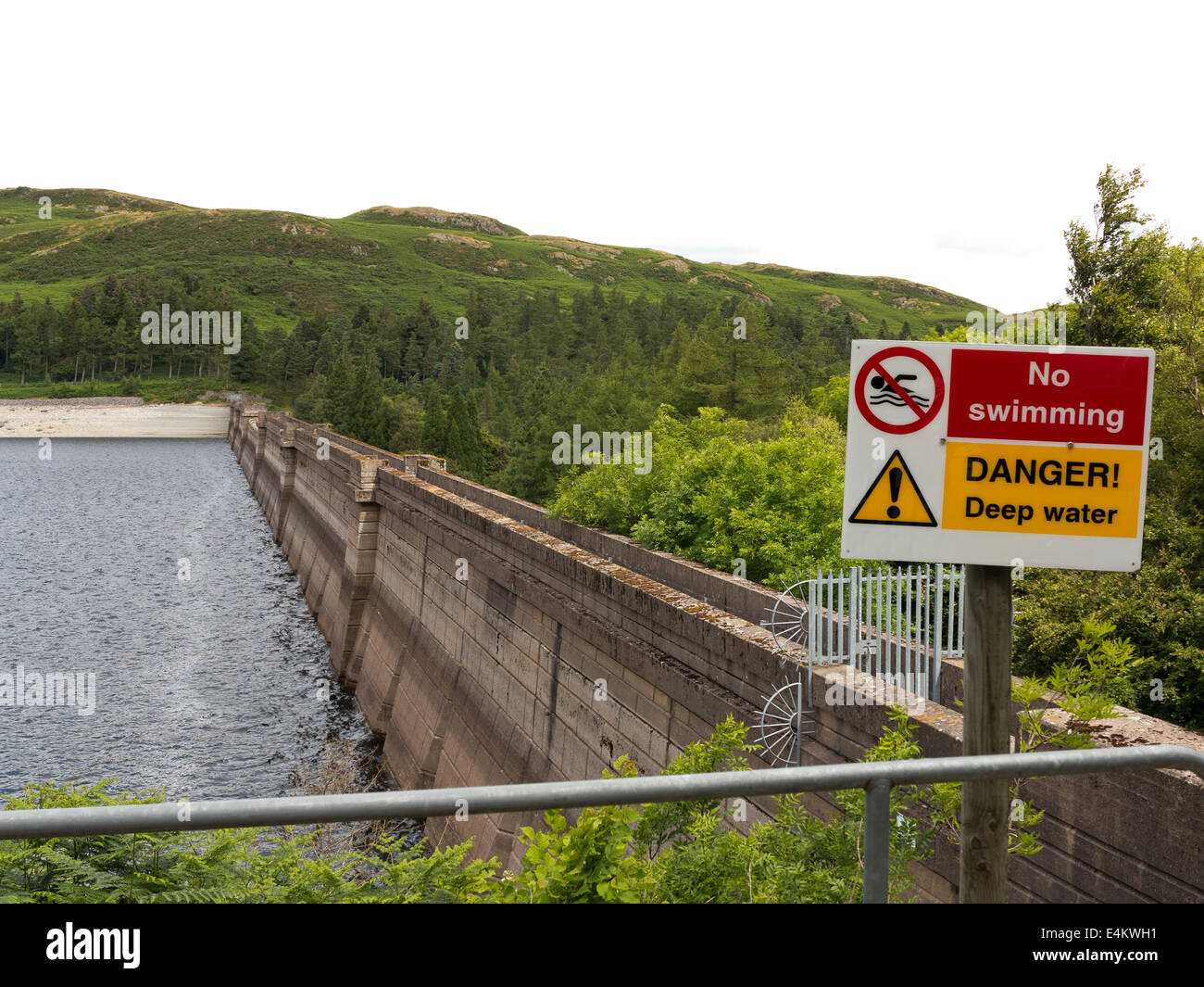 Looking across the inside face of Haweswater dam from the south shore to the north shore showing low water level and danger sign Stock Photo