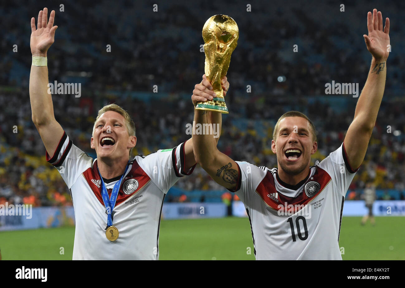 Bastian Schweinsteiger (L) and Lukas Podolski celebrate with the trophy after winning the FIFA World Cup 2014 final soccer match between Germany and Argentina at the Estadio do Maracana in Rio de Janeiro, Brazil, 13 July 2014. Photo: Andreas Gebert/dpa (RESTRICTIONS APPLY: Editorial Use Only, not used in association with any commercial entity - Images must not be used in any form of alert service or push service of any kind including via mobile alert services, downloads to mobile devices or MMS messaging - Images must appear as cstill images and must not emulate match action video footage - No Stock Photo