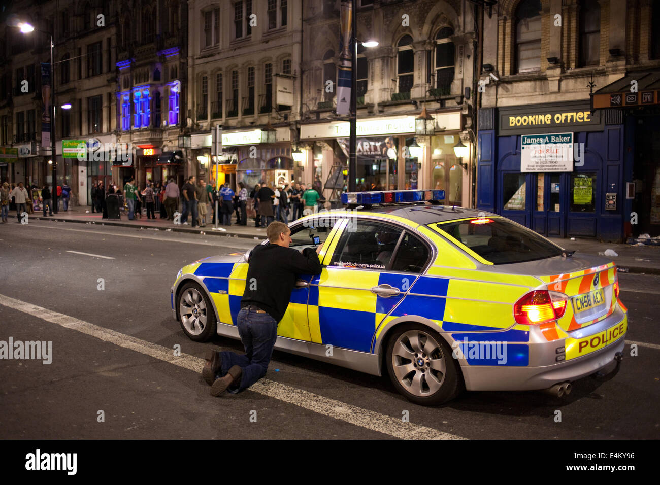 A young man talking to policemen in police car on St Mary Street on a weekend night in Cardiff, Wales, Uk Stock Photo