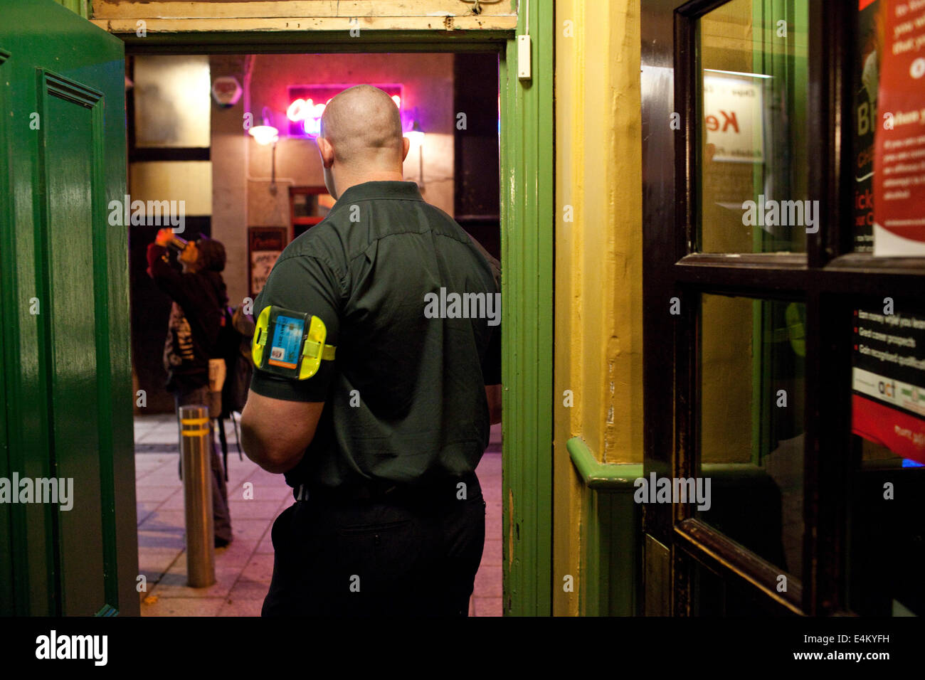 A security guard in a pub doorstep at night in Cardiff, Wales, UK Stock Photo