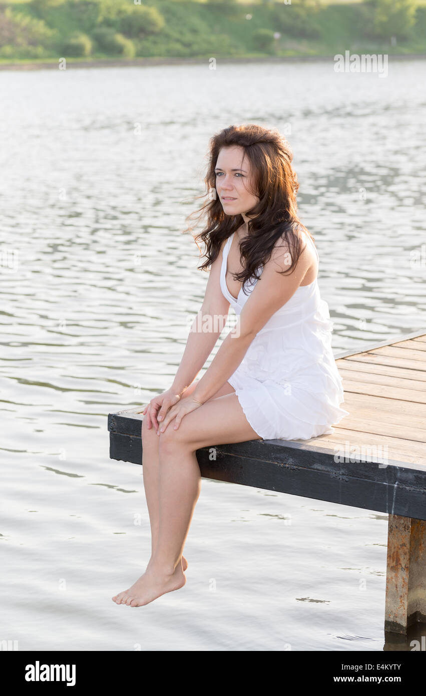Girl sitting on a wooden bridge near the river Stock Photo - Alamy