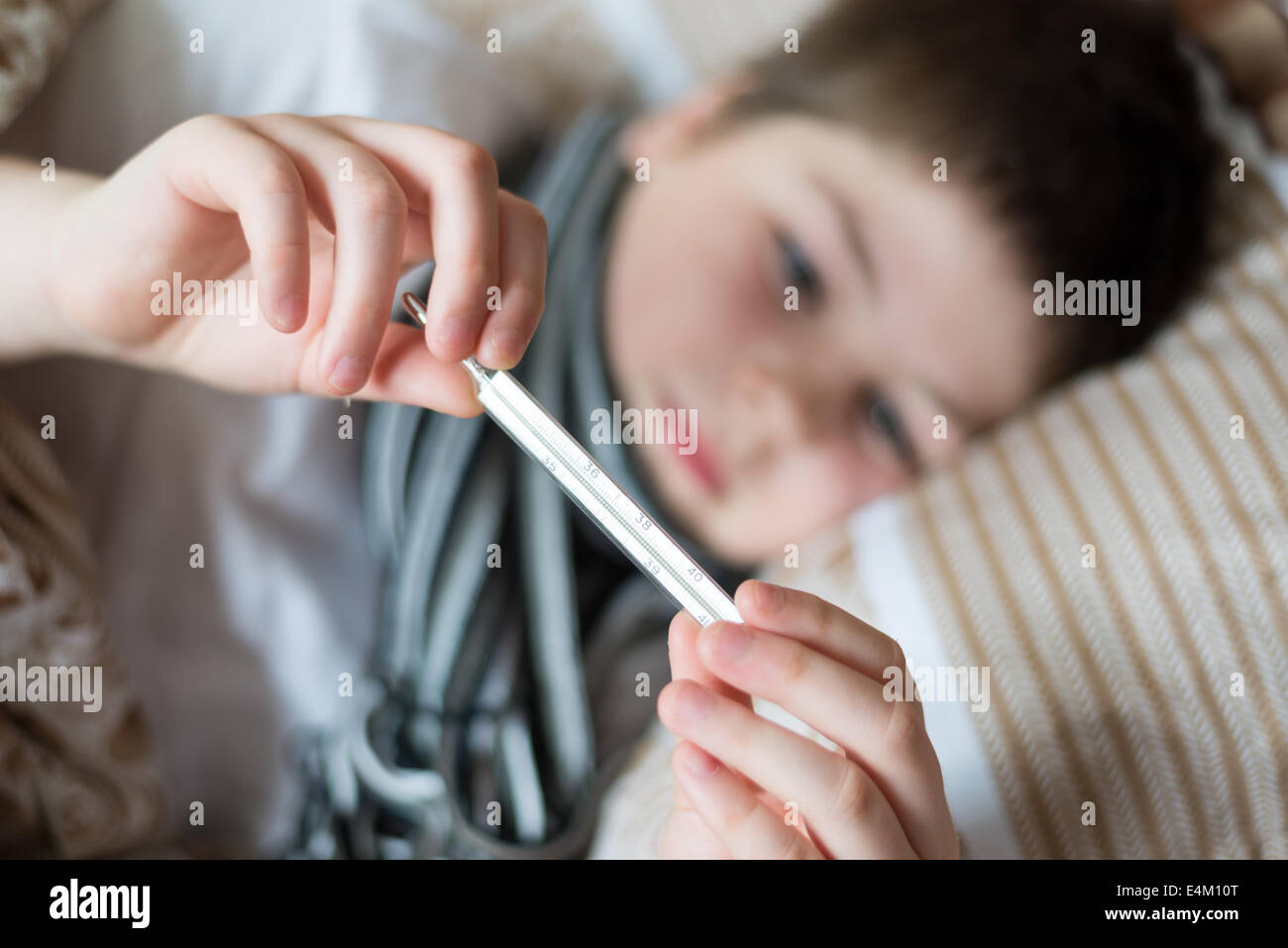 Sick boy with thermometer lying in bed Stock Photo Alamy