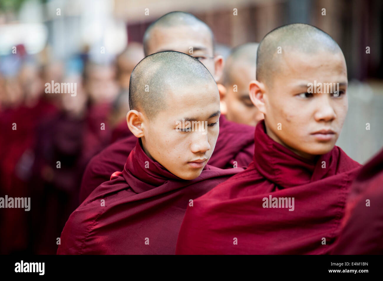 Young Buddhist monks wait in line for food during an Alms Ceremony at the Maha Aung Mye Bonzan Monastery in Mandalay, Myanmar. Stock Photo