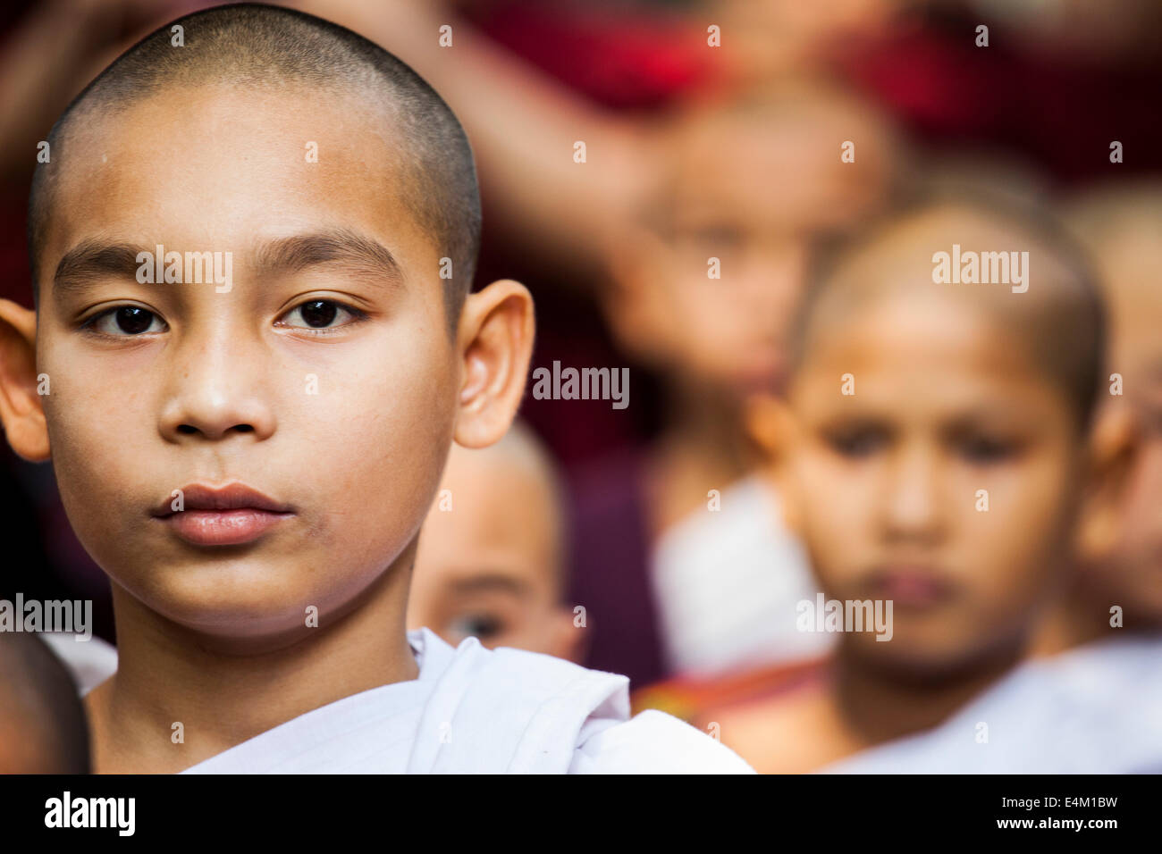 Young Buddhist nuns wait and then line-up to participate in an Alms ceremony and meal at a monastery in Mandalay, Myanmar. Stock Photo