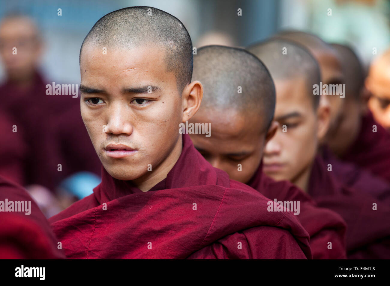 Young Buddhist monks wait in line for food during an Alms Ceremony at the Maha Aung Mye Bonzan Monastery in Mandalay, Myanmar. Stock Photo