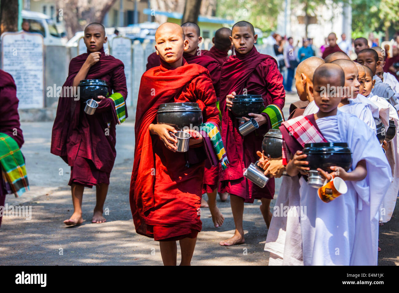 Young Buddhist monks and nuns wait in line for food at an Alms Ceremony at Maha Aung Mye Bonzan Monastery in Mandalay, Myanmar. Stock Photo