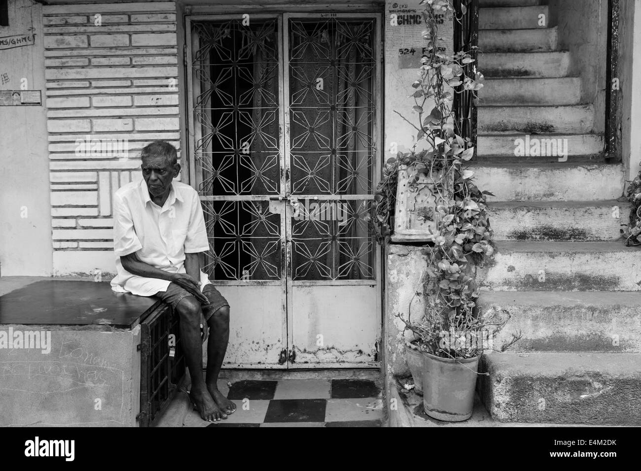 old indian man sitting in front of the house Stock Photo