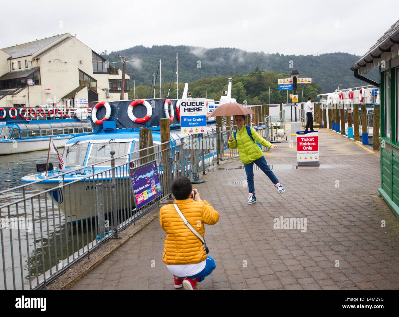 Bowness on Lake Windermere, UK. 14th July, 2014. Tourists making the most of a rainy day Japanese tourists have fun posing in the rain Credit: Gordon Shoosmith/Alamy Live News Stock Photo
