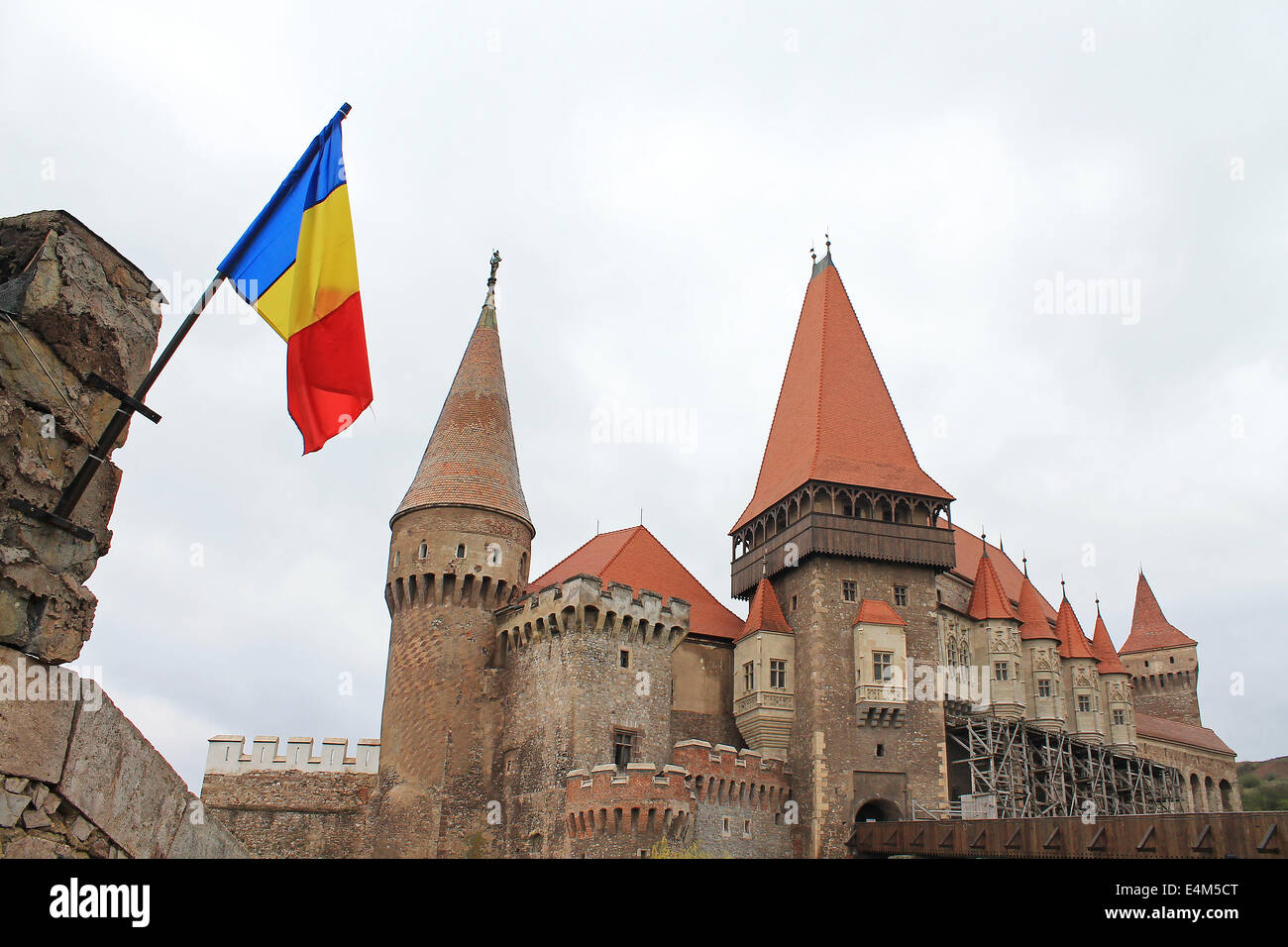 The Hunyad or Corvin Castle from Hunedoara, Transylvania, Romania with the Romanian flag Stock Photo