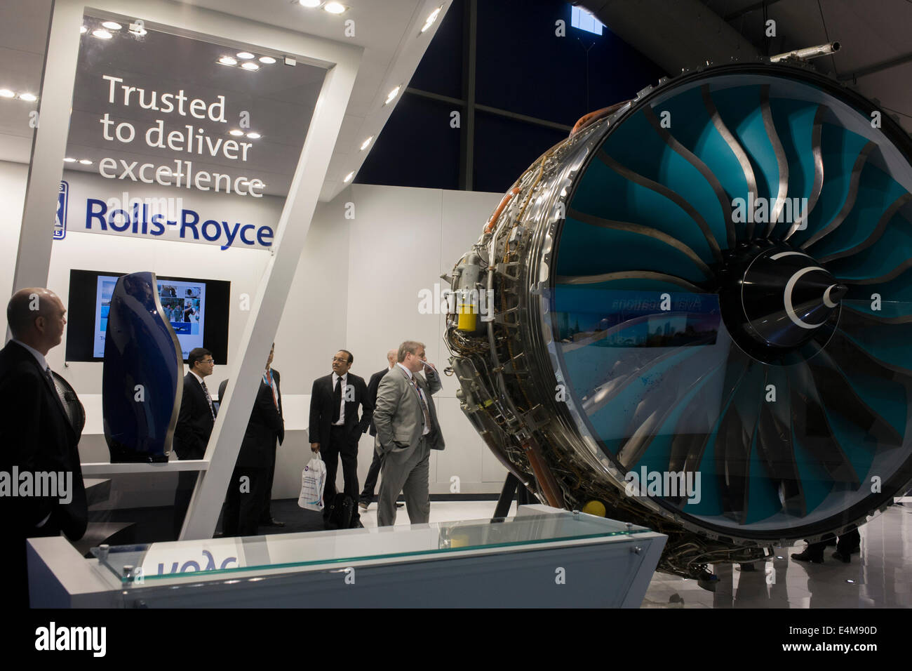A full-size Trent jet engine is admired by delegates visiting British Rolls-Royce manufacturer's exhibition stand at the Farnborough Air Show, England. Rolls-Royce Trent is the name given to a family of three-spool, high bypass turbofan aircraft engines manufactured by Rolls-Royce plc. The engine is named after the River Trent in the Midlands of England. The civil aerospace business is a major manufacturer of aero engines for all sectors of the airliner and corporate jet market. Rolls-Royce powers more than 30 types of commercial aircraft and has almost 13,000 engines in service around  world. Stock Photo