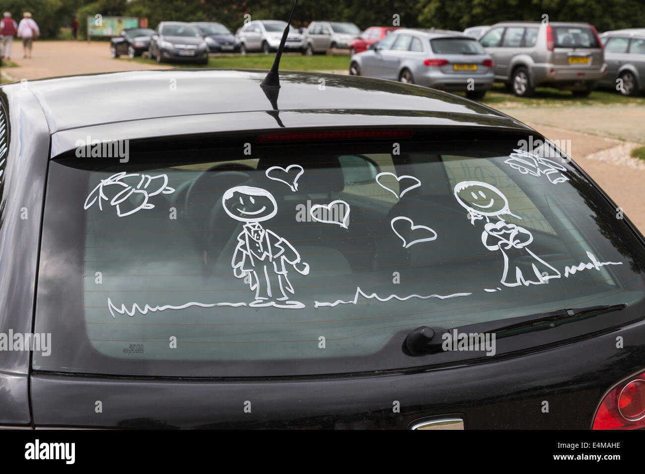 Figures of bride and groom painted on the rear window of a honeymooners' black car Stock Photo