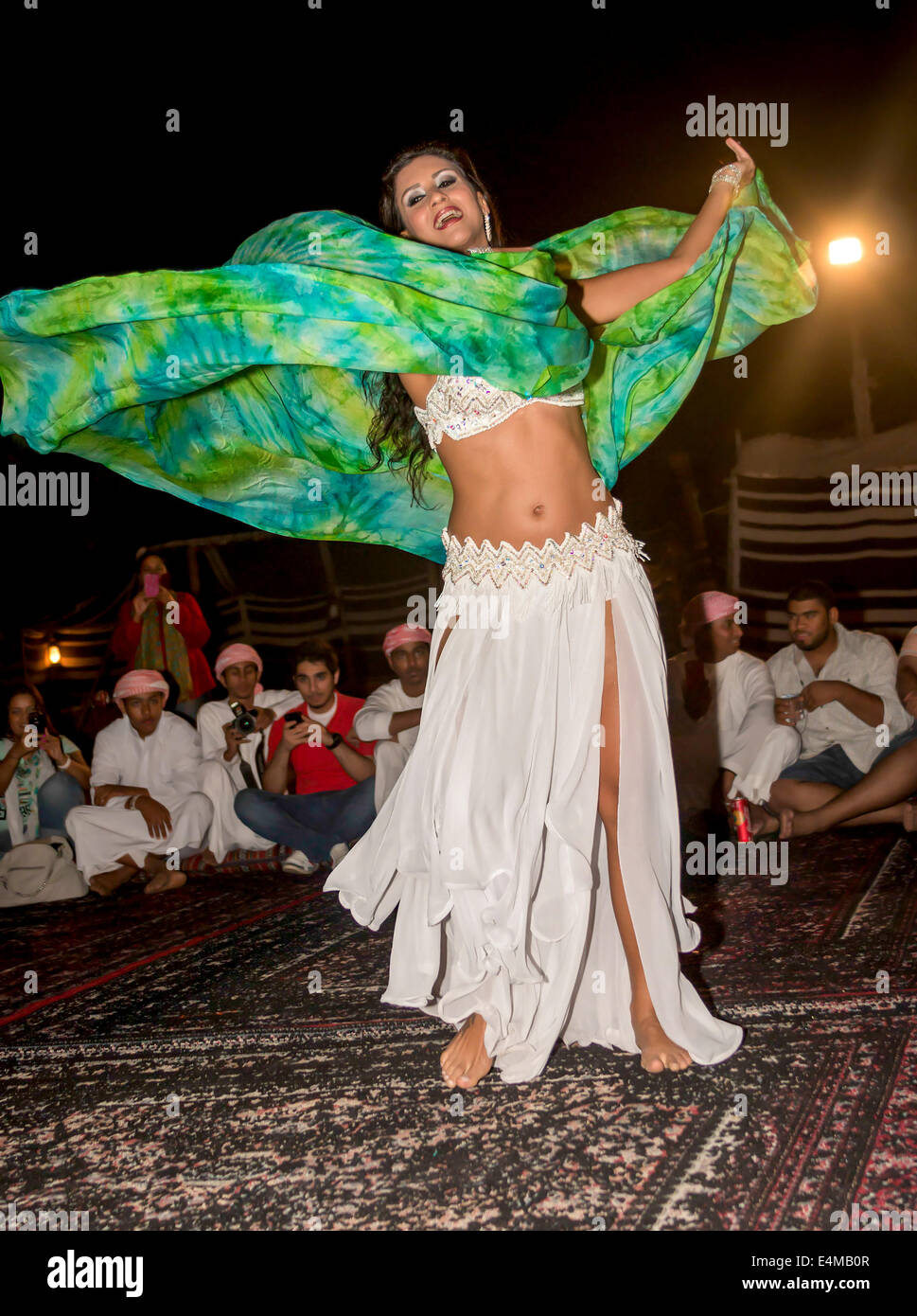 Belly dancer twirls for guests at Bedouin desert safari camp outside Dubai, UAE, where visitors can experience a camel ride, try Stock Photo