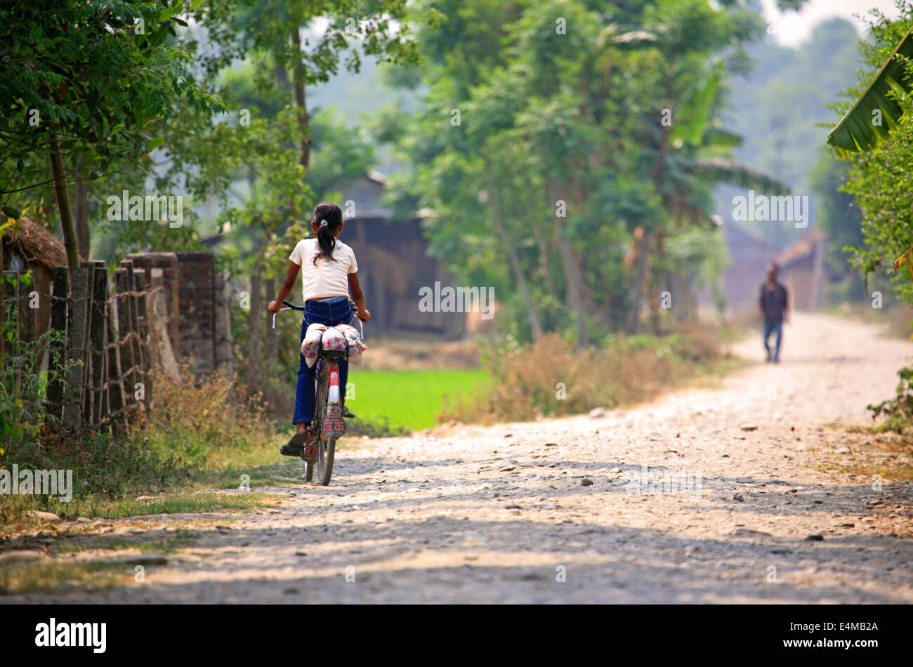 A girl rides in a bike in a rural village in Nepal Stock Photo