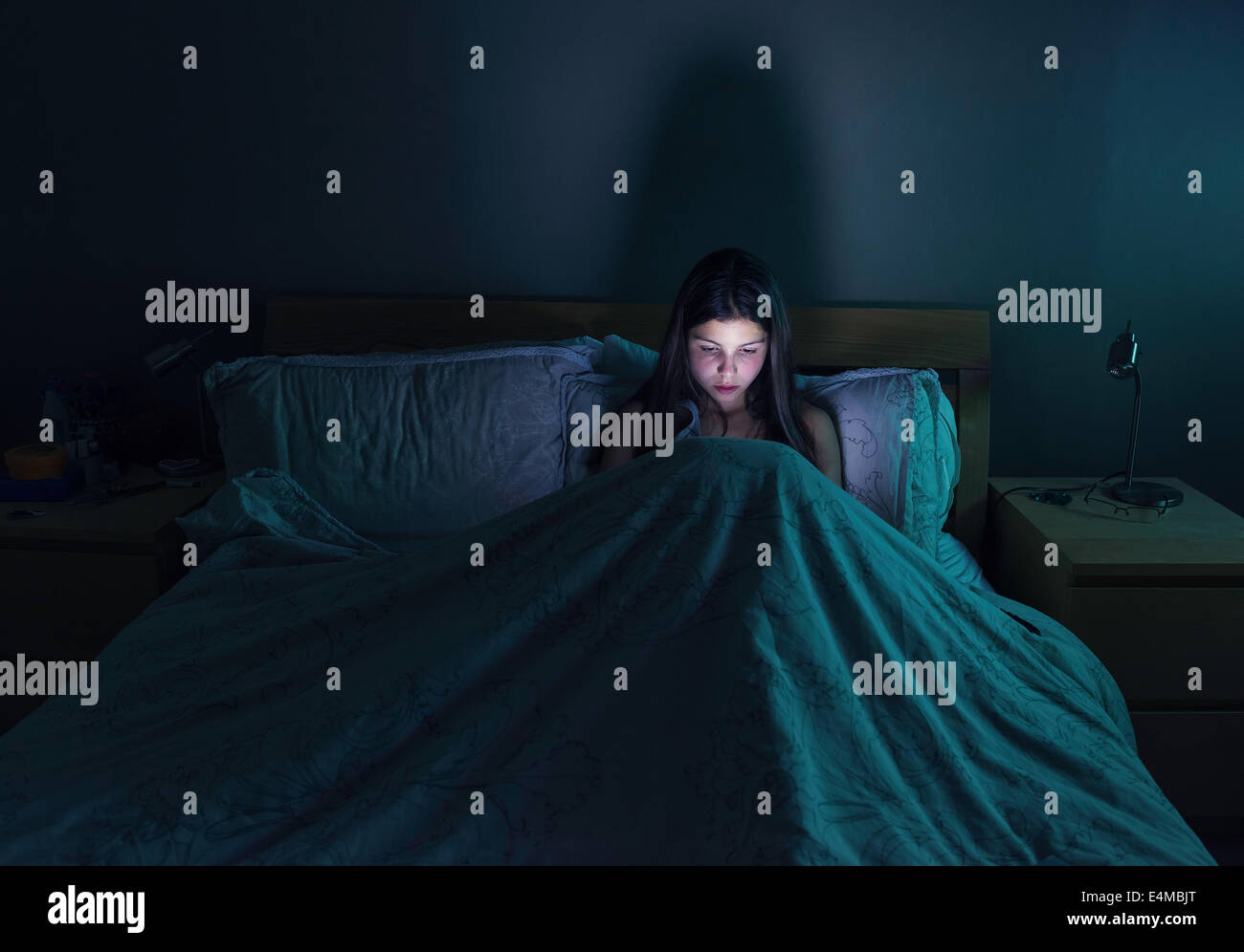 Teenage girl browsing the internet  late at night in  bed Stock Photo