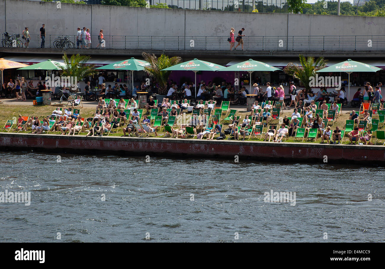 Germany, Berlin, Mitte, people sunbathing on the banks fo the river Spree. Stock Photo