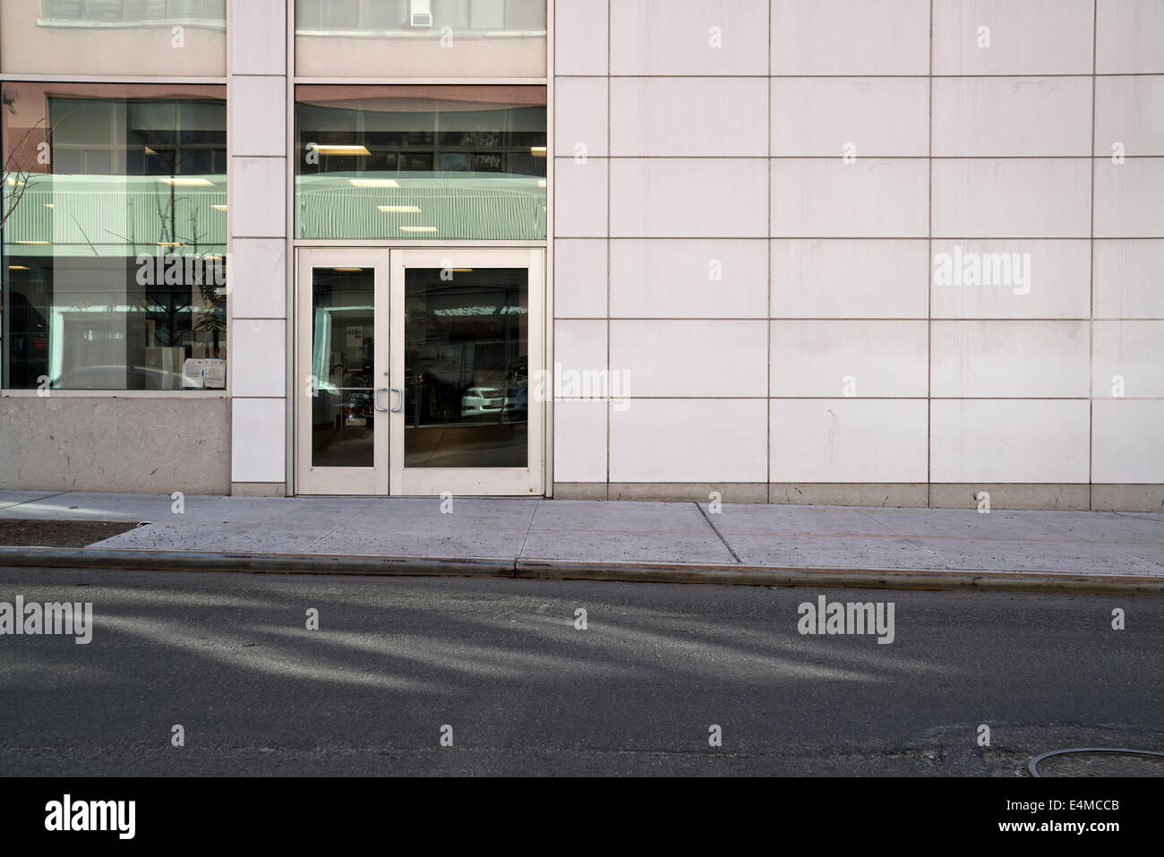 Tiled Wall and Entry Door of an Auto Showroom, Sun Reflections Shining on Pavement. New York City. Stock Photo