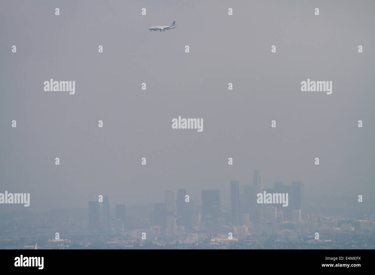 Plane coming into Los Angeles International Airport (LAX), with Downtown Los Angeles seen through smog in distance, California, Stock Photo