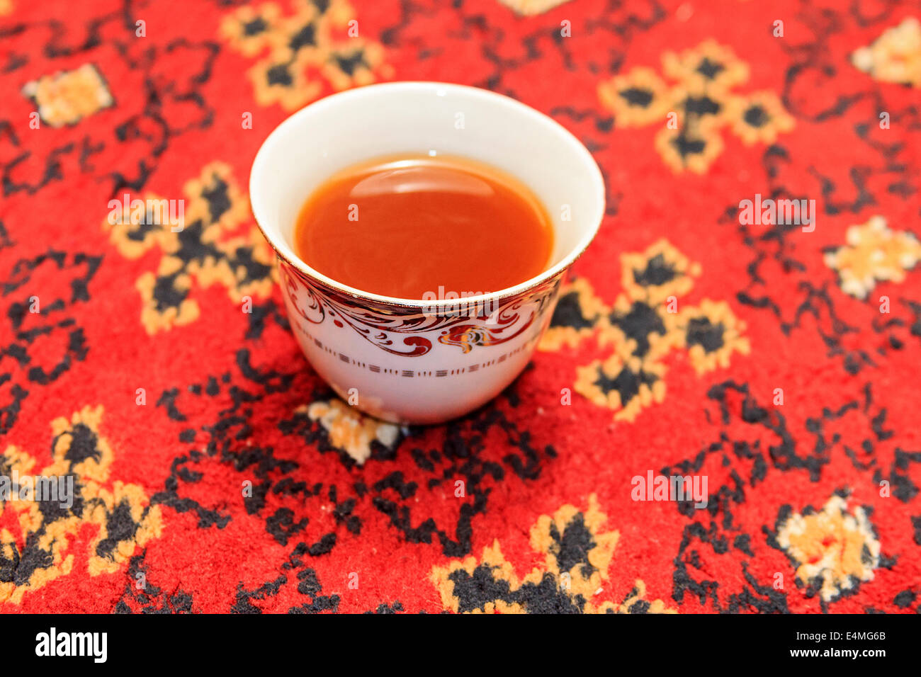Cup of Arab tea against a colorful rug. Stock Photo