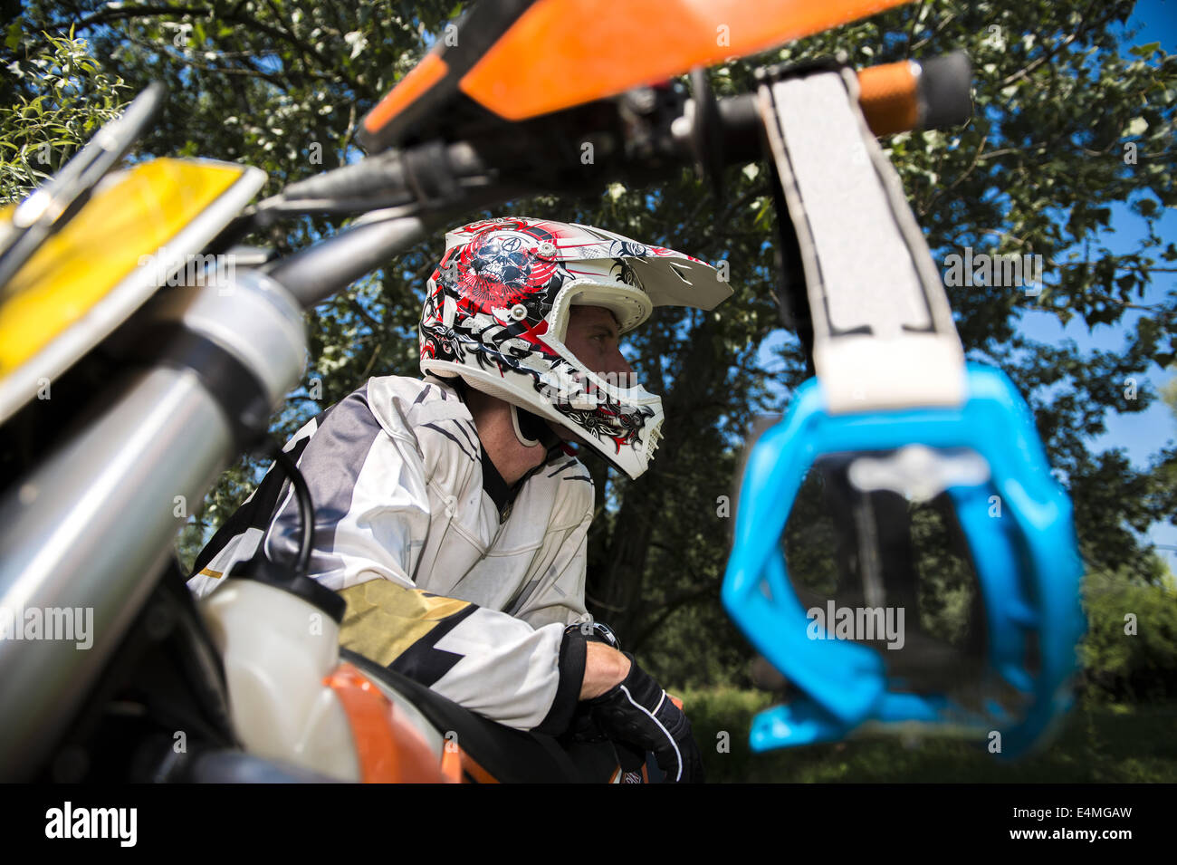 Young Man Relaxing Besides Motocross Bike in Countryside Stock Photo