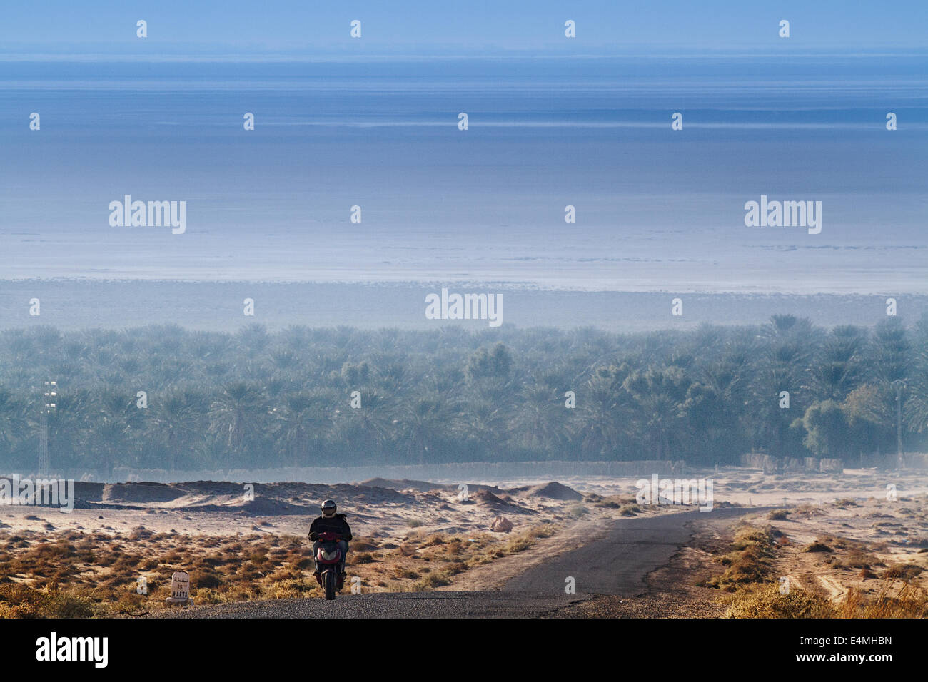 A motorcyclist on a road in the desert Stock Photo