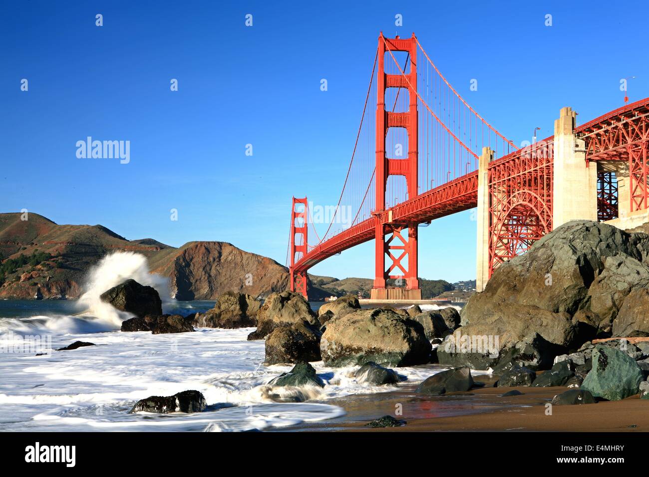 Classic shot of the Golden Gate Bridge from Marshall Beach with a wave crashing, San Francisco, California Stock Photo