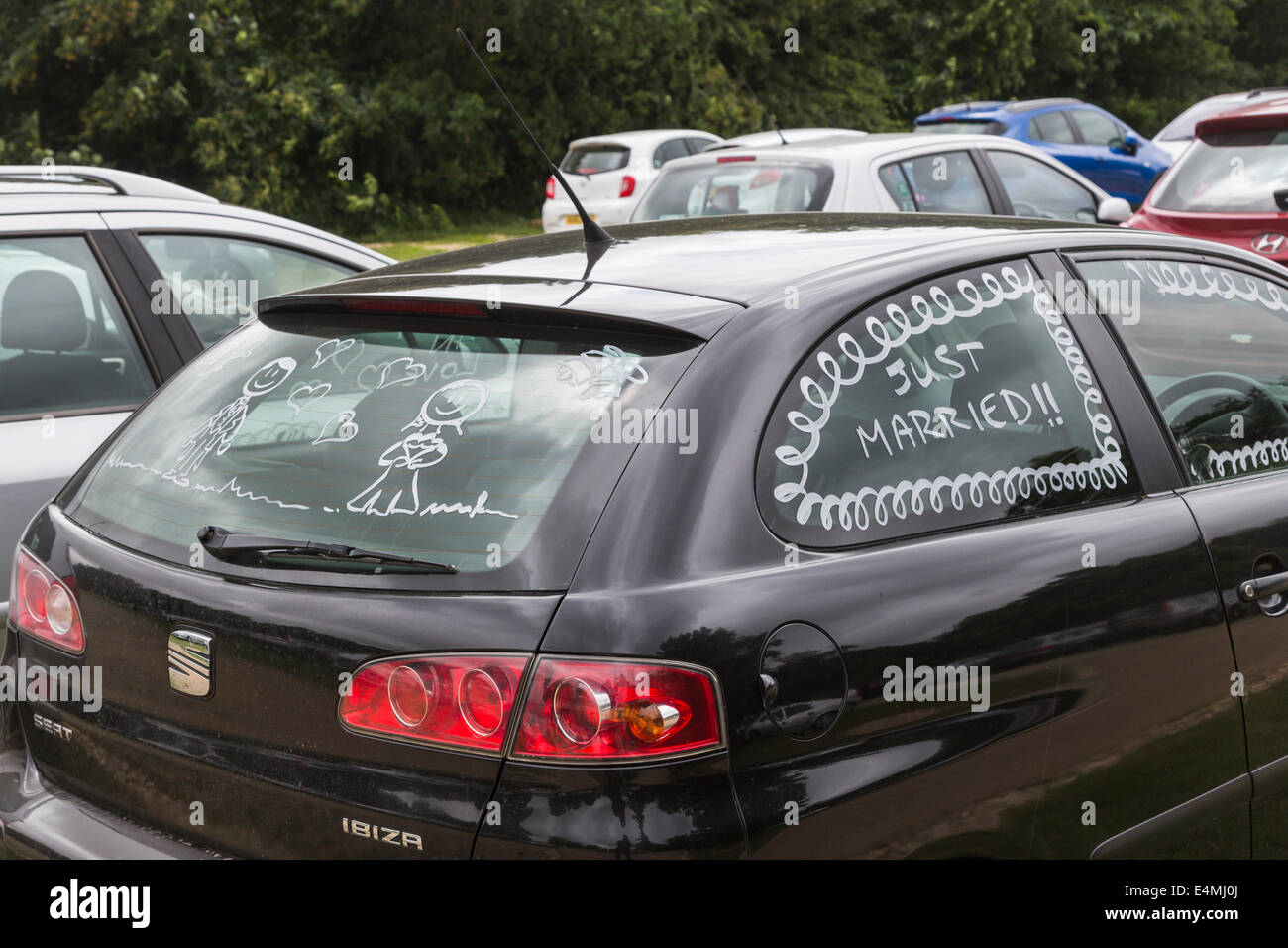 Honeymooners' black car painted with 'Just Married!!' on side window and figures of bride and groom on rear window Stock Photo