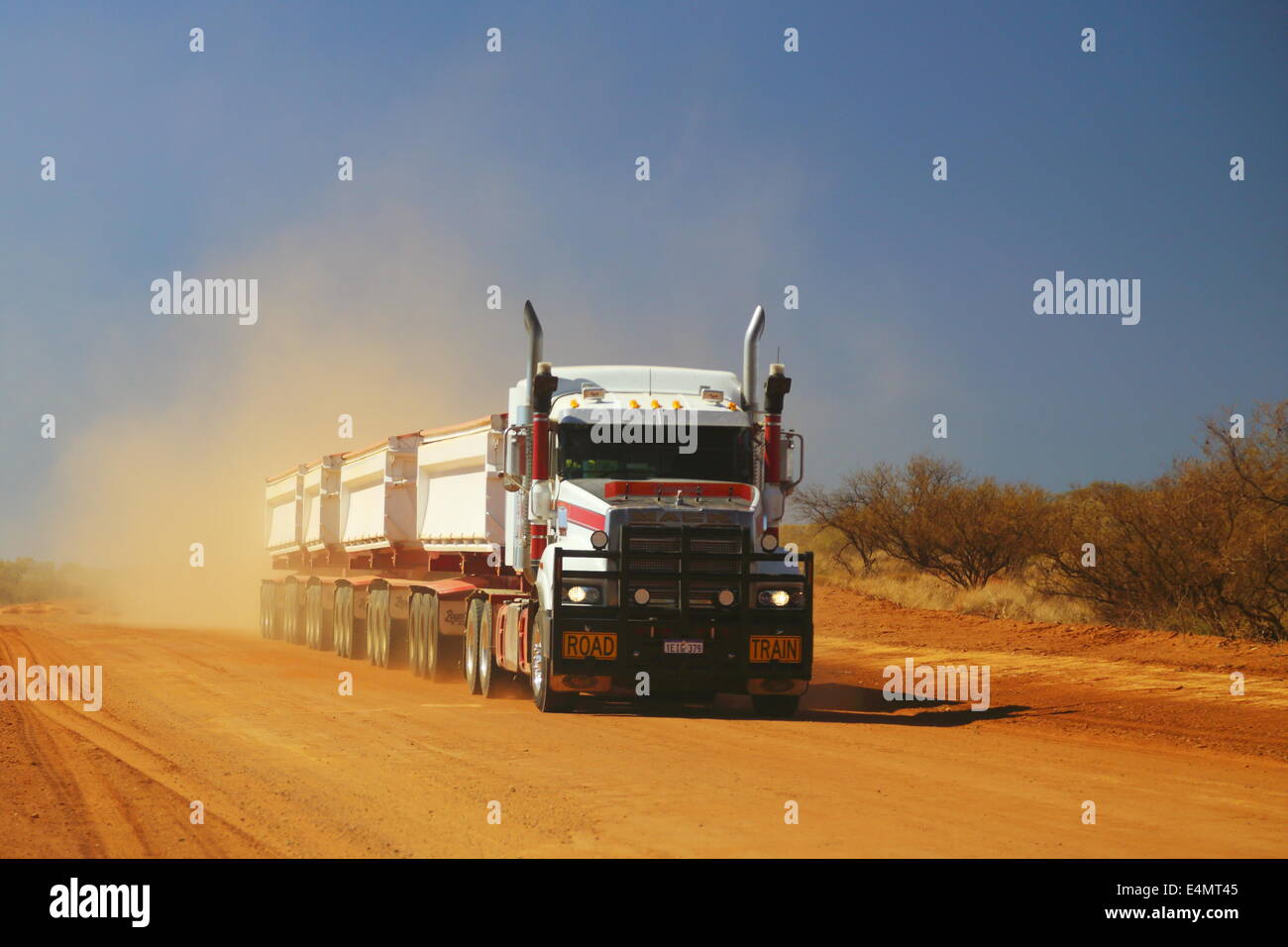 A roadtrain truck transports a load along a dusty dirt road in Western Australia. Stock Photo