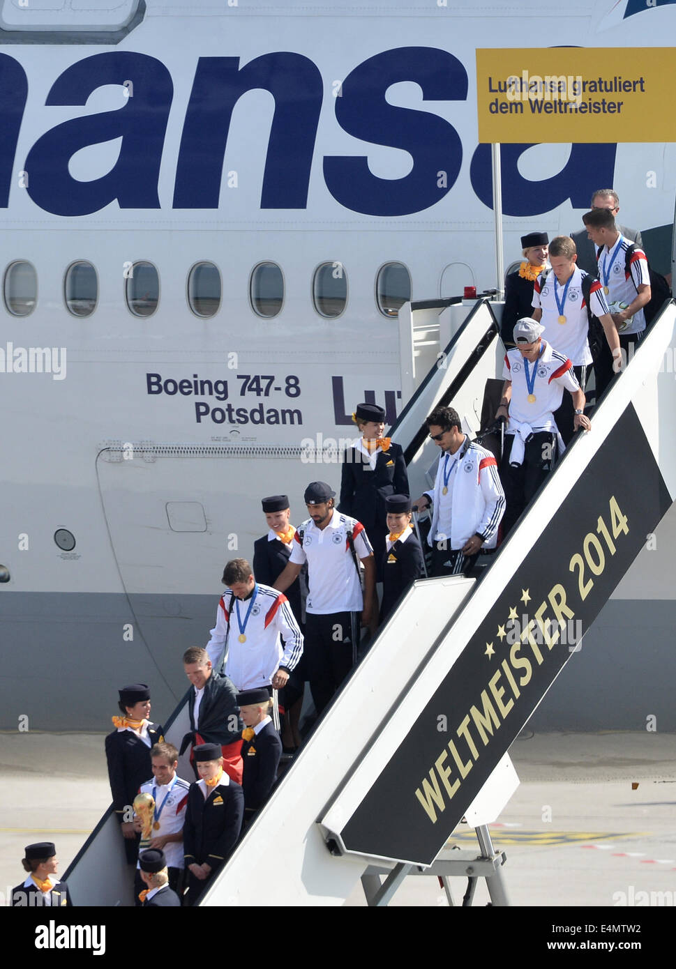 Berlin, Germany. 15th July, 2014. Germany's Philipp Lahm (bottom, C) steps out of the aircraft holding the World Cup trophy in his hands as Germany's national soccer squad arrives at Tegel airport in Berlin, Germany, 15 July 2014. Team Germany won the Brazil 2014 FIFA Soccer World Cup final against Argentina by 1-0, winning the World Champion title for the fourth time after the 1954, 1974 and 1990 World Cups. PHOTO: BERND VON JUTRCZENKA/dpa/Alamy Live News Stock Photo