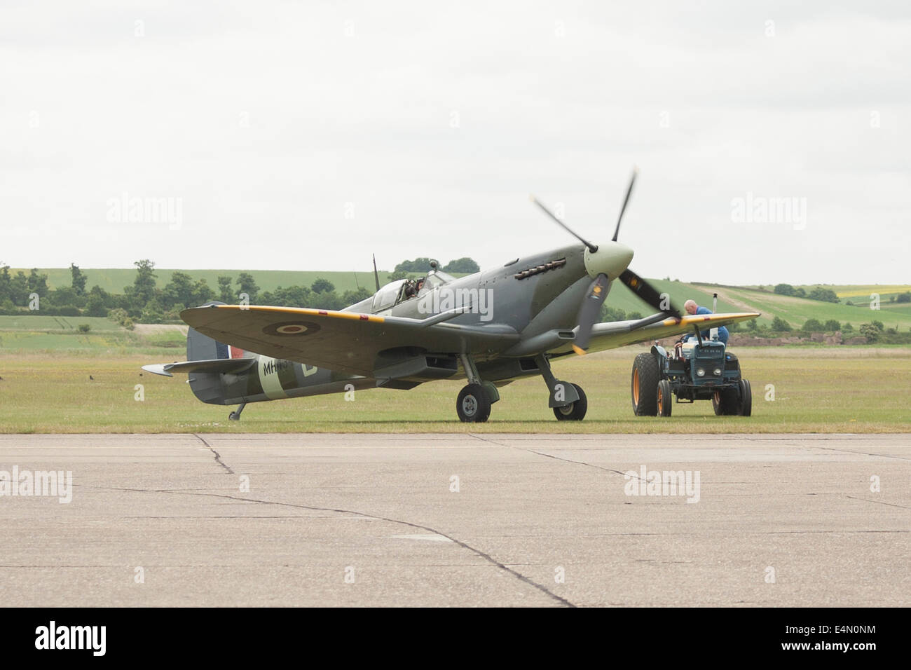 Supermarine Spitfire on the edge of the runway with tractor at Imperial War Museum Duxford, United Kingdom Stock Photo