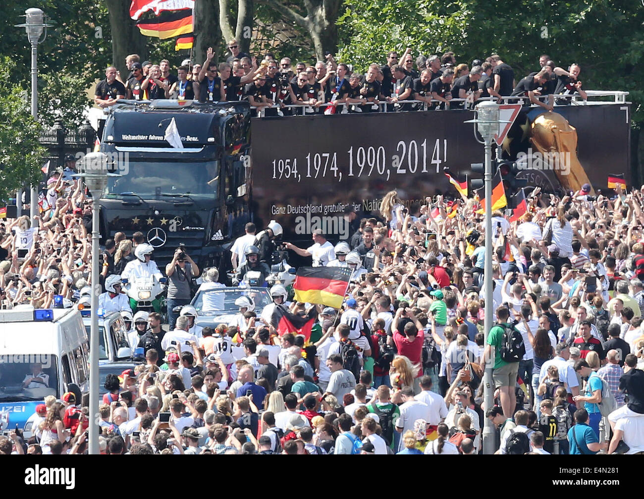 Berlin, Germany. 15th July, 2014. The German national soccer team is celebrated by fans during their drive to Brandenburg Gate in Berlin, Germany, 15 July 2014. The German team on 13 July 2014 had won the Brazil 2014 FIFA Soccer World Cup final against Argentina by 1-0 to win the title for the fourth time after 1954, 1974 and 1990. Photo: WOLFGANG KUMM/DPA/Alamy Live News Stock Photo