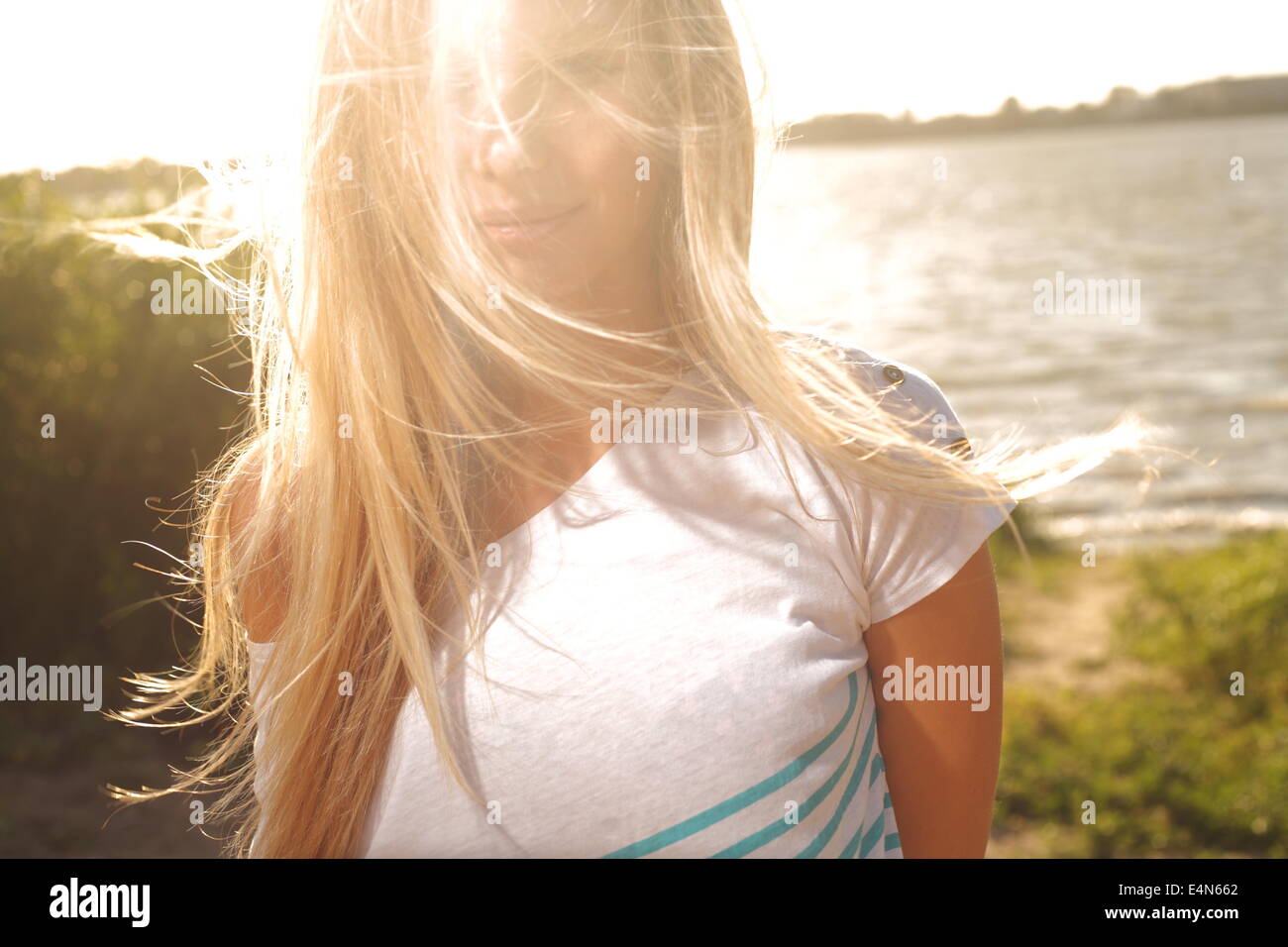 girl sitting near river against sun Stock Photo - Alamy