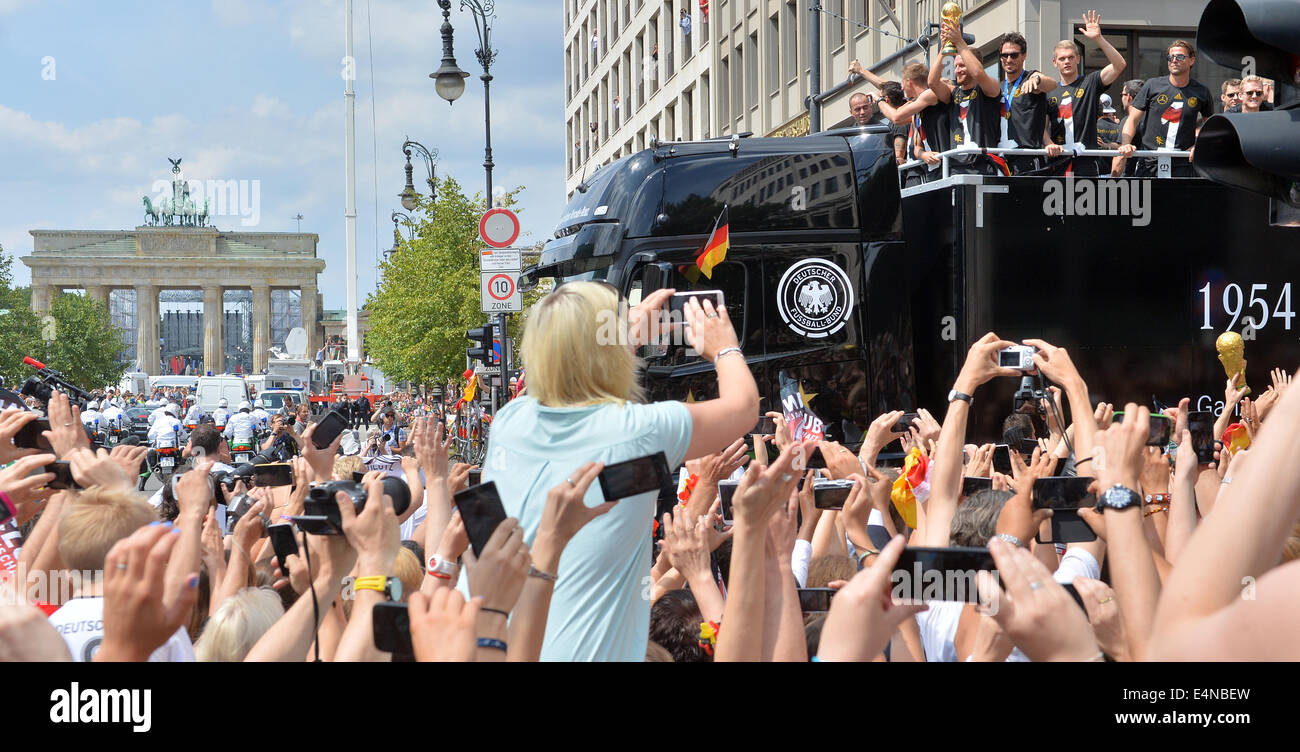 Berlin, Germany. 15th July, 2014. The German national soccer team is celebrated by fans during their drive to Brandenburg Gate in Berlin, Germany, 15 July 2014. The German team on 13 July 2014 had won the Brazil 2014 FIFA Soccer World Cup final against Argentina by 1-0 to win the title for the fourth time after 1954, 1974 and 1990. Photo: HENDRIK SCHMIDT/DPA/Alamy Live News Stock Photo