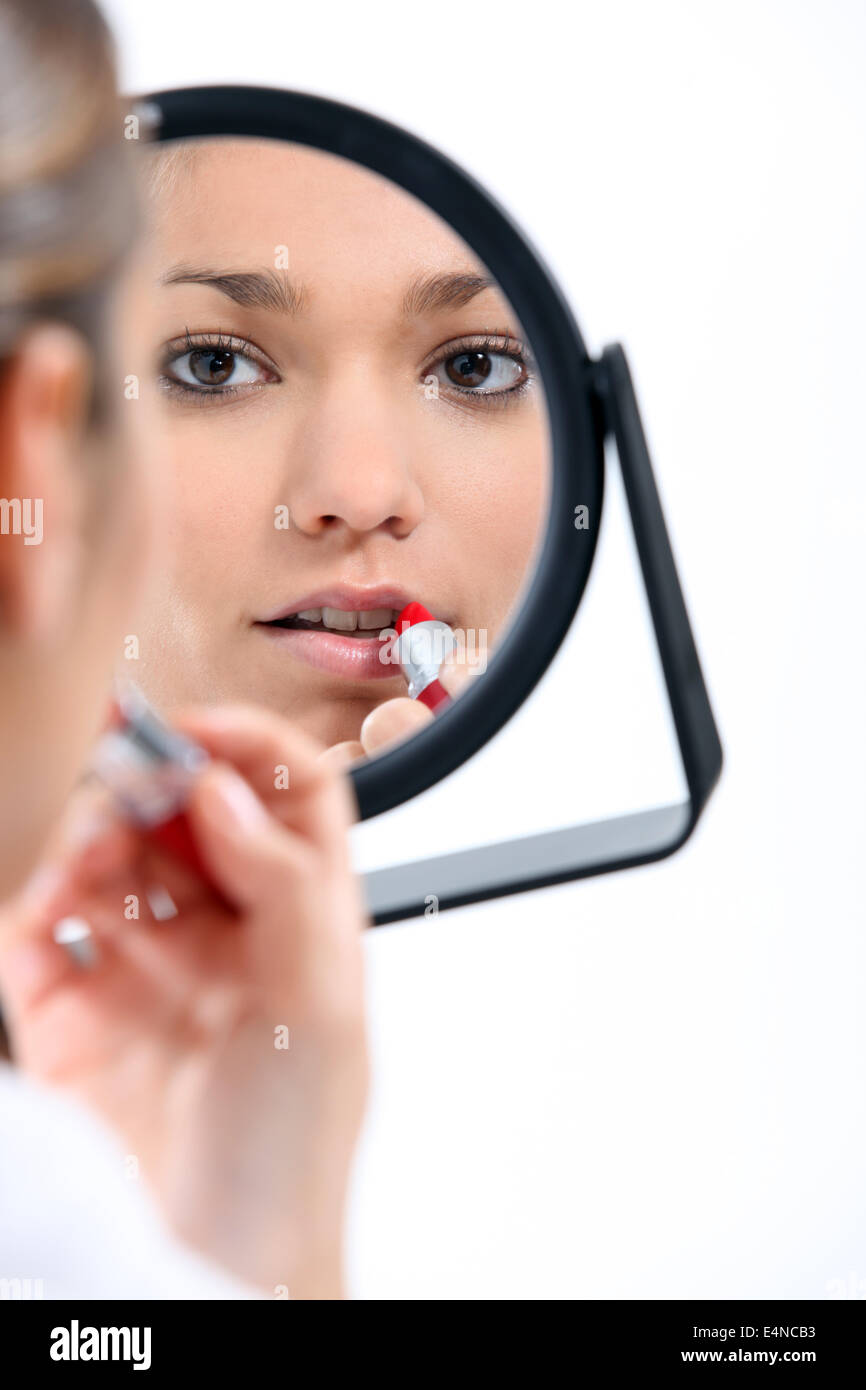 Woman applying make-up in mirror Stock Photo