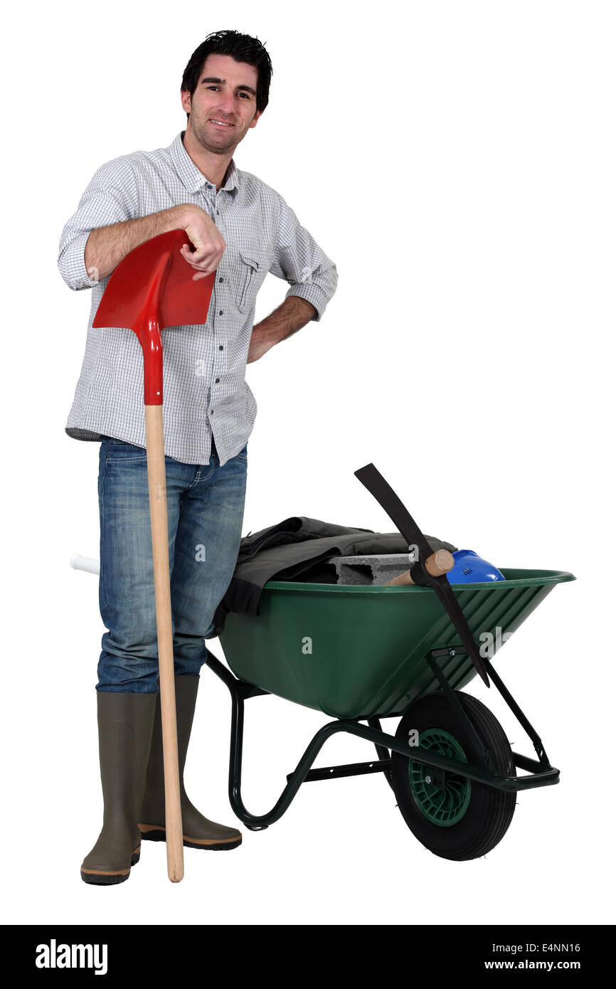 Man stood with spade and wheelbarrow Stock Photo