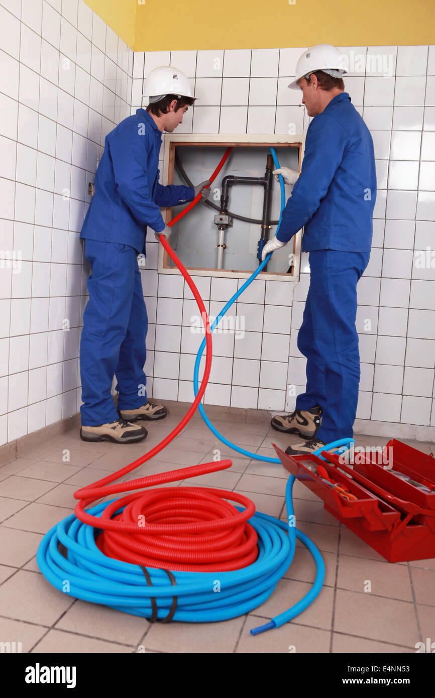 Plumbers installing new hot and cold pipes Stock Photo