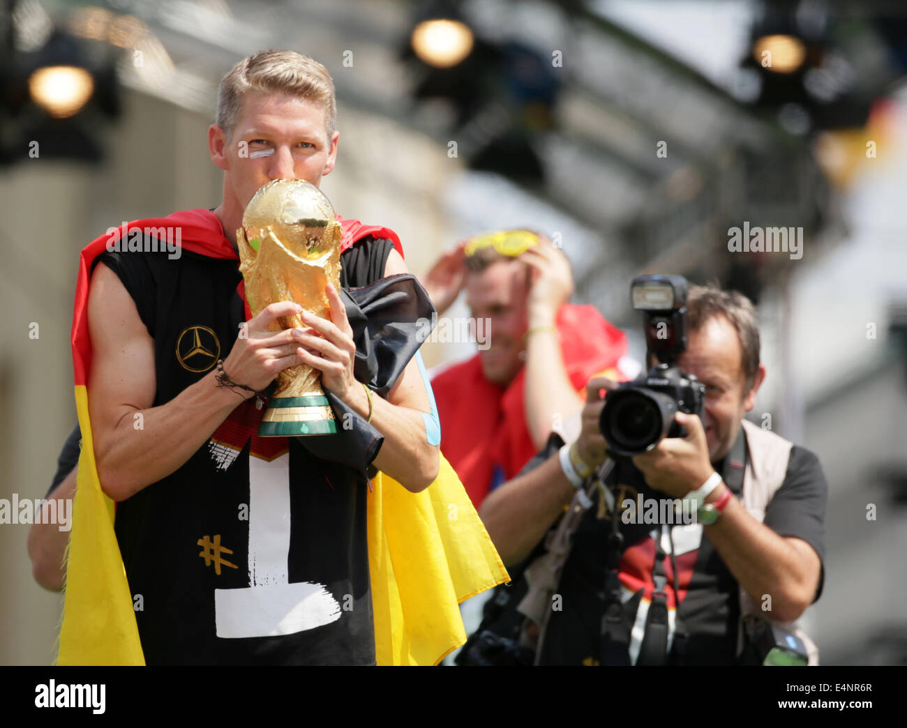 Berlin, Germany. 15th July, 2014. Germany's Bastian Schweinsteiger (L) kisses the World Cup trophy on stage during the welcome reception for Germany's national soccer team in front of the Brandenburg Gate, Berlin, Germany, 15 July 2014. The German team won the Brazil 2014 FIFA Soccer World Cup final against Argentina by 1-0 on 13 July 2014, winning the world cup title for the fourth time after 1954, 1974 and 1990. Photo: Michael Kappeler/dpa/Alamy Live News Stock Photo