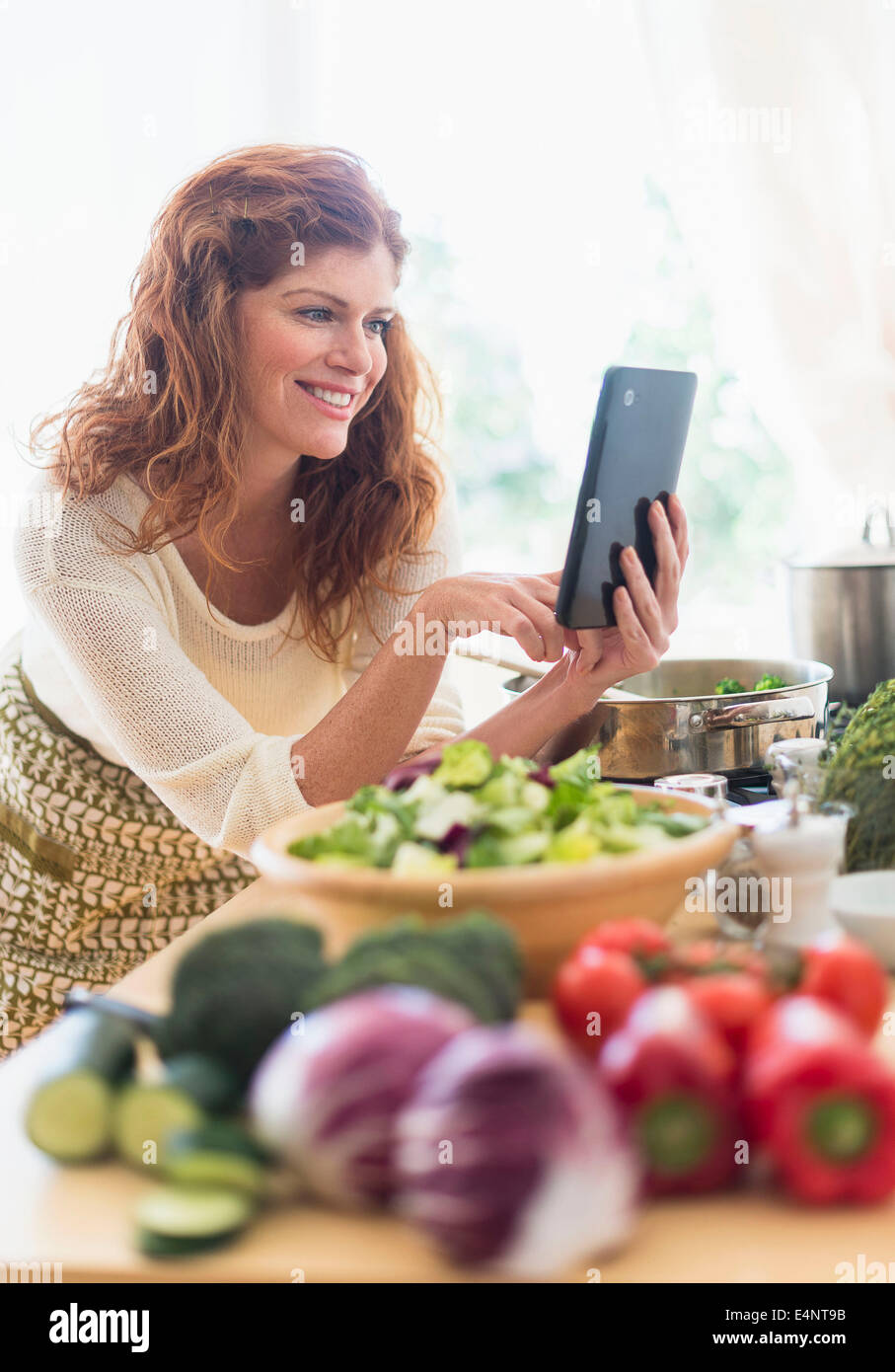 Woman cooking and using digital tablet in kitchen Stock Photo