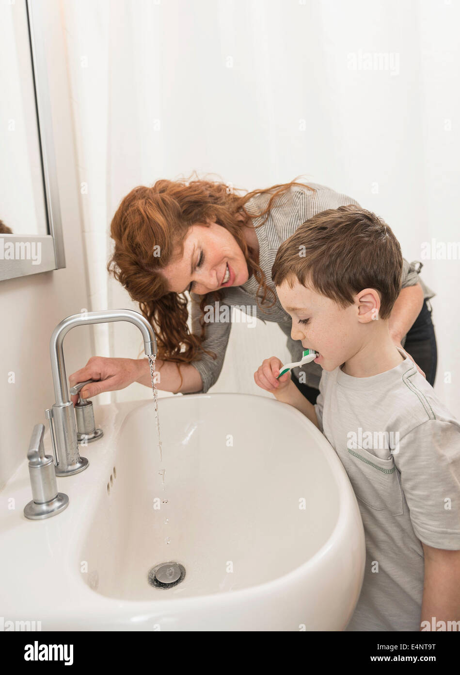 Son (6-7) and mother brushing teeth Stock Photo