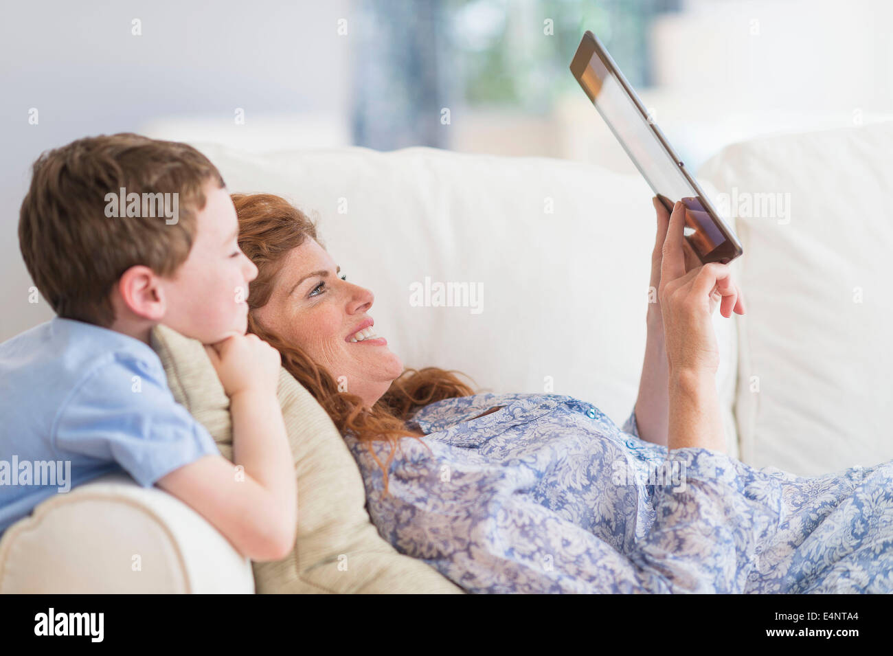 Mother and son (6-7) lying on sofa using digital tablet Stock Photo