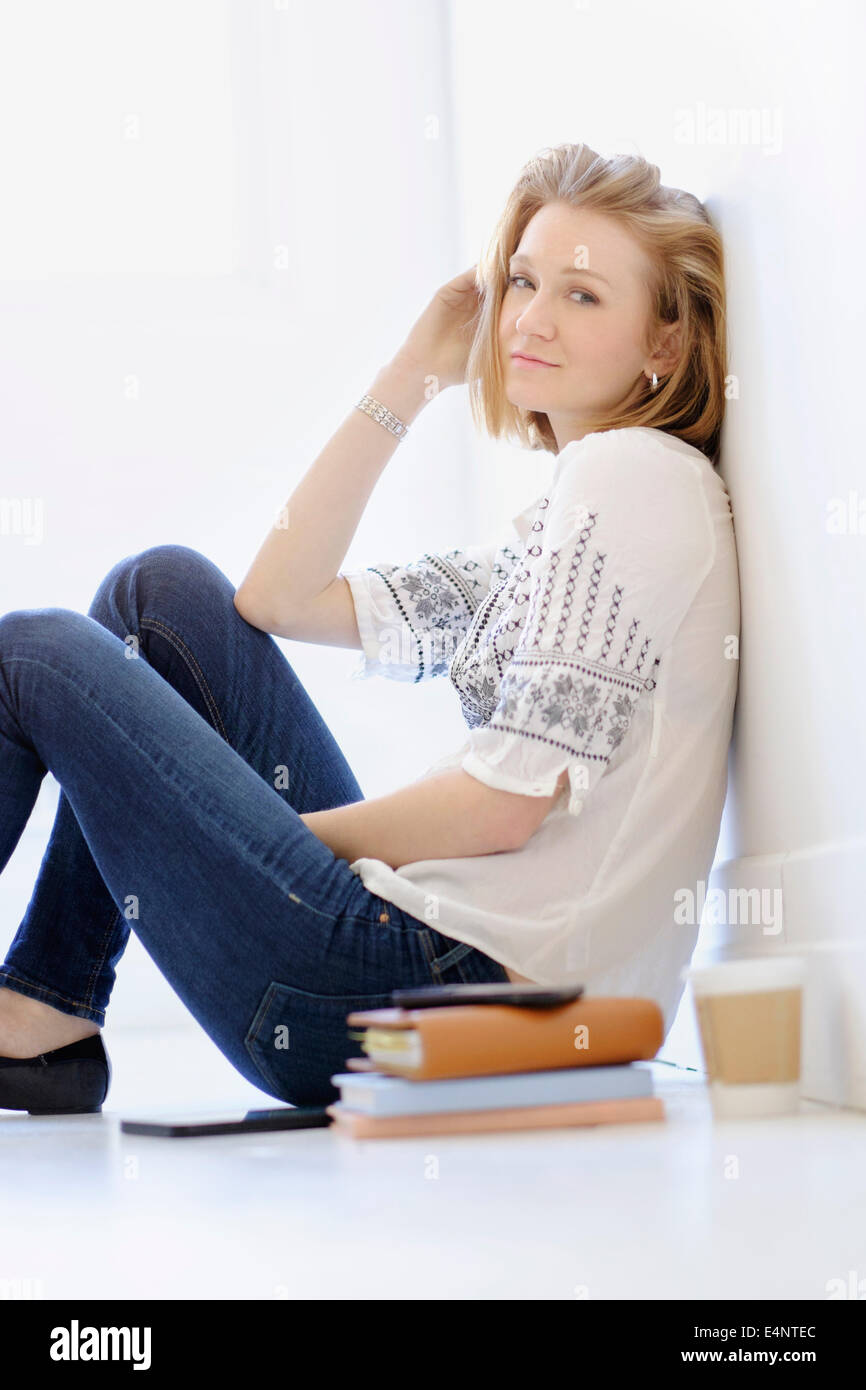 Portrait of young woman sitting on floor Stock Photo - Alamy