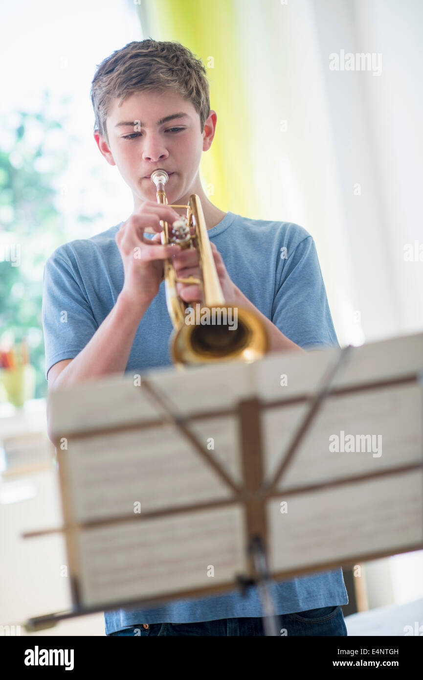 Young boy practicing playing trumpet in living room at home Stock