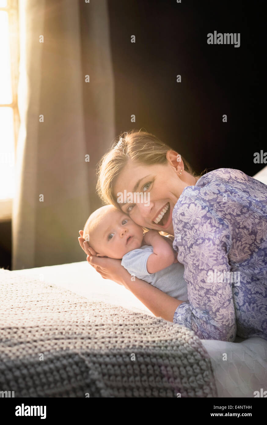 Portrait of smiling Mother holding baby boy (2-5 months) in bedroom Stock Photo