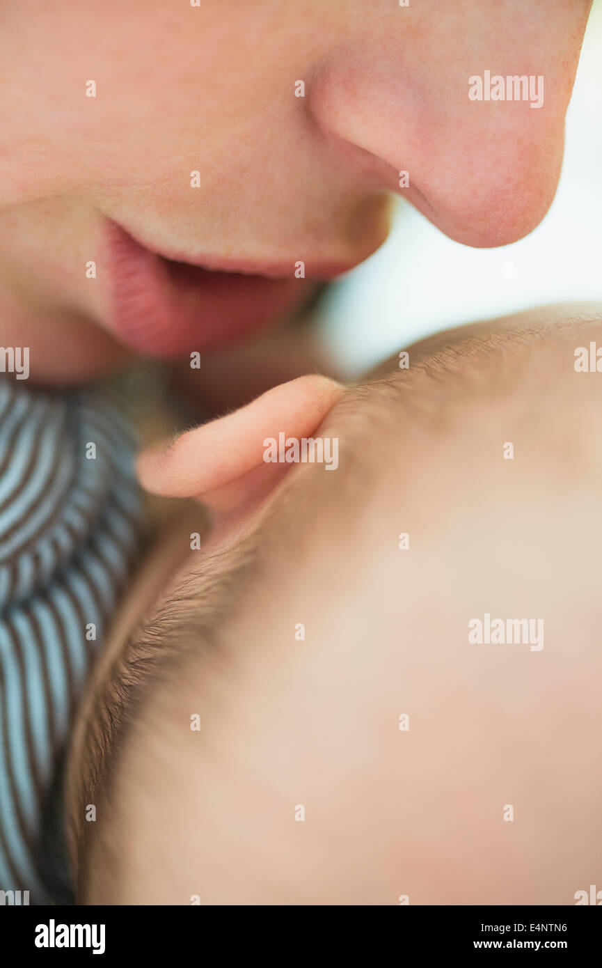 Close up of mother's mouth whispering into baby boy's (2-5 months) ear Stock Photo